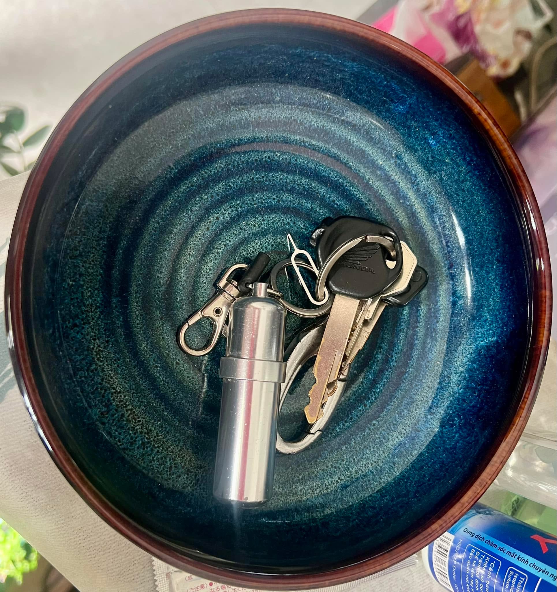 Chuyện cái tô chìa khoá.

Tôi lên Shopee tìm một cái tô về để đựng chìa khoá. Nhìn thấy shop có tô đẹp tôi quất thêm 3 cái để dùng gì khác thì dùng. Bạn bè đến nhà chơi hỏi: ủa sao có cái tô nằm đây? Mà có cả chìa khoá trong đó.

Coi phim từ nhỏ đến lớn tôi thấy tụi Âu/Mỹ hiện đại mở cửa bước vào nhà là quăng chìa khoá vào cái tô. Không hiểu nổi tại sao! Càng xem nhiều phim càng thấy nhiều cái tô chén dĩa bát thau chậu đựng chìa khoá. Có căn nhà đầu tiên tôi quên không làm theo, do cũng chưa hiểu tại sao, mí phần ở một mình thì không cầu kì. Đến căn nhà thứ 2 có người ở chung, tôi đã luôn nghĩ đến chuyện sắm cái tô!

Trước khi xắm cái tô, tôi bắt cái móc có 4 cái khoen để treo chìa khoá lên tường. Cái móc này lâu ngày bị dính bụi đổi luôn từ đen sáng xám bụi do không ai dùng. Chìa khoá nào treo đó cũng đổi màu bụi. 5 năm ở đây tôi toàn để chìa khoá lên cái tủ gần cái khoen!

Vậy là tôi lên Shopee mua 1 cái tô thiệt đẹp để ngay đó.

Cái tô để quăng chìa vô không trượt như dĩa hay không có tô.
Cái tô để bỏ chìa vô thì phát ra âm thanh như tiếng chuông của người Nhật gõ báo đồ ăn có rồi, báo tôi về rồi.
Cái tô để âm thanh bỏ vô êm dịu giữa 12h khuya thể hiện sự quan tâm dành cho người đang ngủ của người về khuya. Âm thanh phát ra trên cái tô đôi khi cũng cho biết cảm xúc của người này.
Cái tô để tô cho đẹp nhà
Cái tô có thể để nhiều chìa mà khi lấy lên không phải gỡ rối như móc treo.
Cái tô để ăn một chút tinh tuý “ở nhà Tây” mà ai cũng thèm.
Cái tô để đựng.